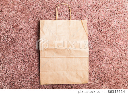 An empty paper bag lays on pink a  carpet 86352614