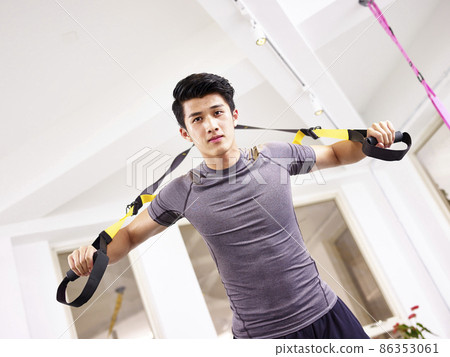young asian man exercising in gym using fitness straps 86353061