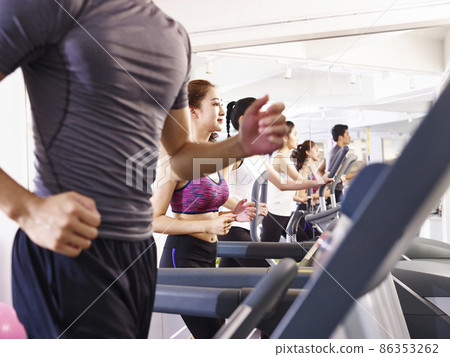 young asian adult working out on treadmill, focus on the girl in the middle 86353262
