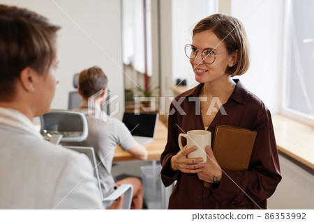 Smiling Young Woman Talking to Colleague Smiling Young Woman Talking to Colleague 86353992