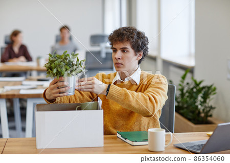 Young Man Putting Plant on Desk 86354060