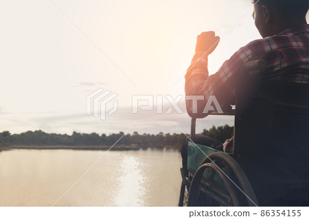 Young disabled man with blue sky background.He is alone and sitting on wheelchair. 86354155