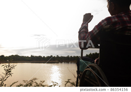 Young disabled man with blue sky background.He is alone and sitting on wheelchair. 86354156