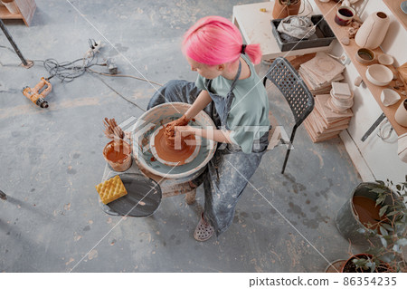 Woman crafter making clay dishes in pottery room 86354235