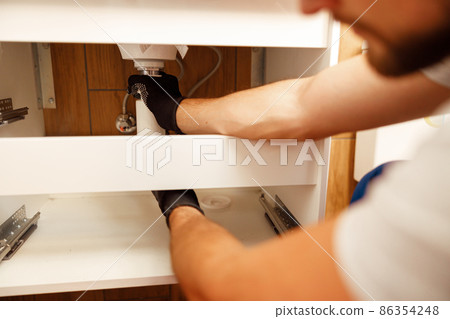 Closeup of hands of professional plumber fixing sink, changing water pipe in apartment Closeup of hands of professional plumber fixing sink, changing water pipe in apartment 86354248