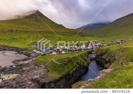 View of Gjogv village at misty sunset. Eysturoy, Faroe islands, Denmark 86354529