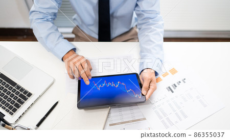 Working Man Conept The male employee sitting at his desk, holding a tablet, and touching the screen of his work 86355037