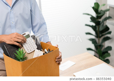 Resignation Concept The man in light blue shirt standing at the desk and putting the calculator and other stuff into the box 86355040
