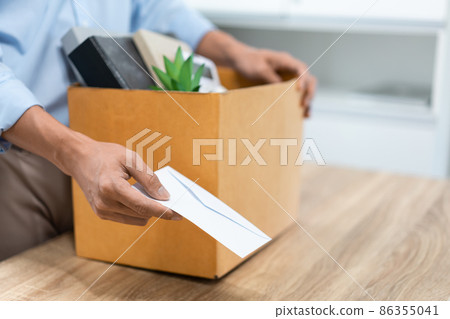Resignation Concept The male officer standing, putting his box of his belongs on the desk and handing the white letter to someone Resignation Concept The male officer standing, putting his box of his belongs on the desk and handing the white letter to someone 86355041