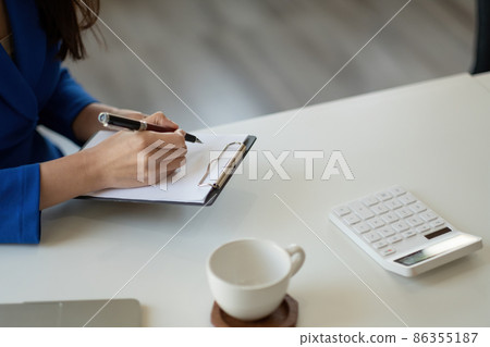 Closeup image of a woman writing and taking note on notebook in office, accounting financial concept Closeup image of a woman writing and taking note on notebook in office, accounting financial concept 86355187