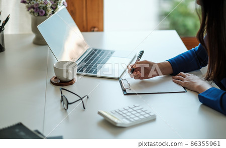Cropped photo of woman writing making list taking notes in notepad working or learning on laptop indoors- educational course or training, seminar, education online concept 86355961