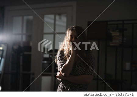 Serious beautiful young woman in dress posing for the camera. Serious beautiful young woman in dress posing for the camera. 86357171