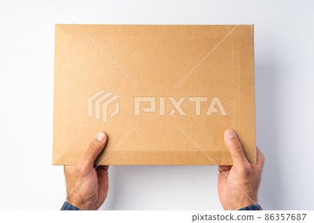 Male hand holding parcel post against white background 86357687