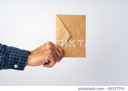 Male hand holding small envelope against the white surface Male hand holding small envelope against the white surface 86357741