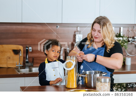 Mom and daughter cook spaghetti in the kitchen Mom and daughter cook spaghetti in the kitchen 86358168