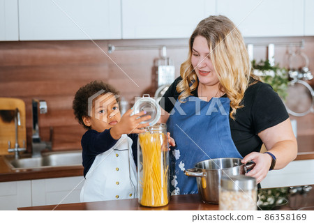 Mom and daughter cook spaghetti in the kitchen Mom and daughter cook spaghetti in the kitchen 86358169