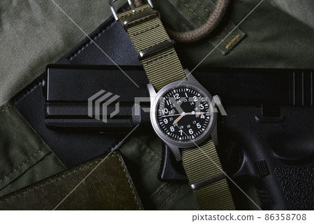Vintage military watch wallet and pistol on army green background, Classic timepiece wristwatch Vintage military watch wallet and pistol on army green background, Classic timepiece wristwatch 86358708