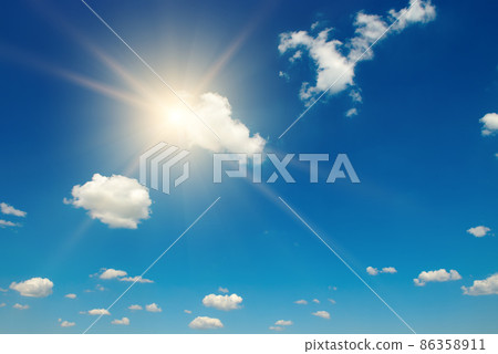 Blue sky with white fluffy clouds and bright sun 86358911