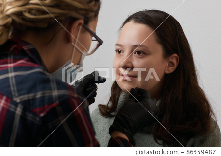 Closeup of a young woman's visage with piercing septum hanging from her nose. Closeup of a young woman's visage with piercing septum hanging from her nose. 86359487