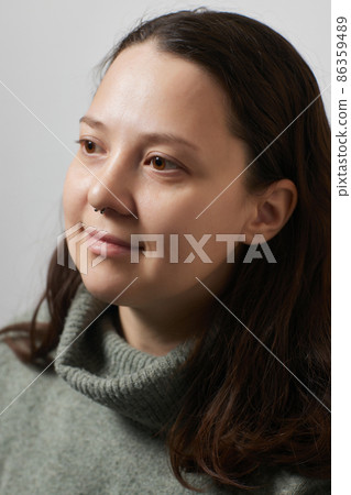 Closeup of a young woman's visage with piercing septum hanging from her nose. Closeup of a young woman's visage with piercing septum hanging from her nose. 86359489