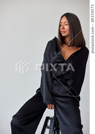 Young slim woman model in sunglasses, black military uniform stands with her legs wide apart and arms crossed at chest. Young slim woman model in sunglasses, black military uniform stands with her legs wide apart and arms crossed at chest. 86359573