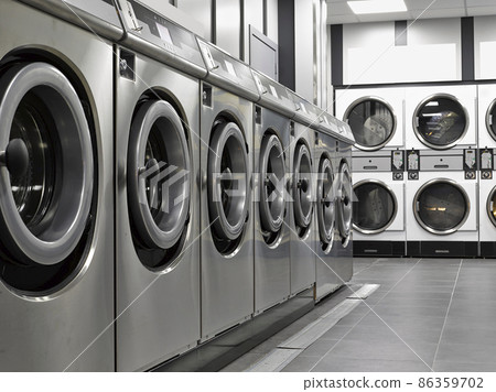 Row of industrial washing machines in a public laundromat 86359702