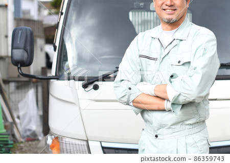中間人穿著工作服，雙臂交叉在卡車前 86359743