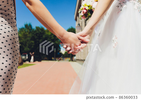 Concept of love between young women : Two women standing behind their backs holding hands together in the rainy season. Concept of love between young women : Two women standing behind their backs holding hands together in the rainy season. 86360033