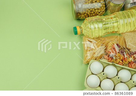 Donation food green background with copy space. Flat lay. Top view, mock up. Rice, canned food, butter, eggs, pasta. Food donation or food delivery concept. Online shopping during quarantine. 86361089