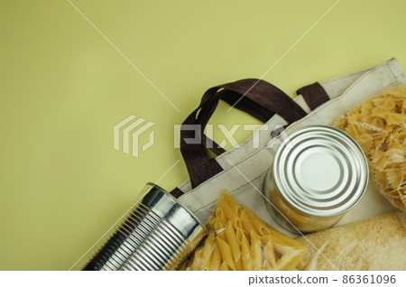 Food donations in a linen bag. Food delivery in an eco bag, canned food, pasta. Eco bag with food supplies. View from above. The concept of donation and mercy. Copy space 86361096
