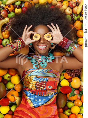 Beautiful black woman smiles closing her eyes with apricots 86361562
