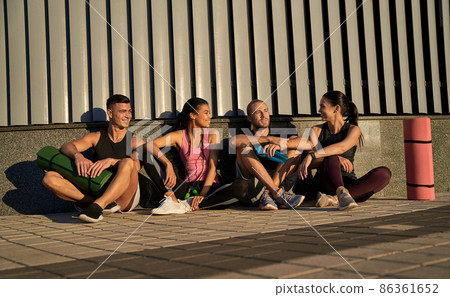 Happy four friends chatting after training outdoors Happy four friends chatting after training outdoors 86361652