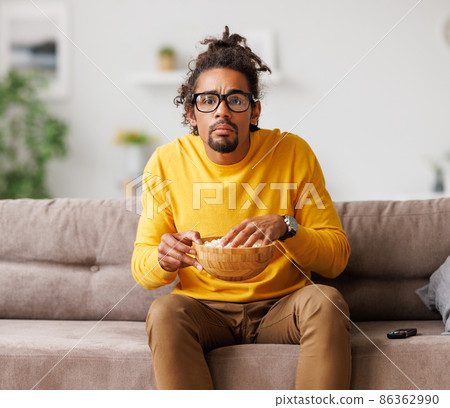 Bored tired african american man watch tv with remote control while relaxing at home 86362990