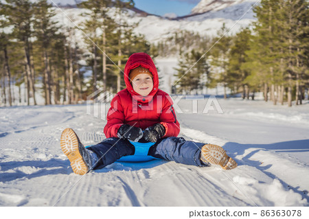 happy and positive little boy enjoying sledding and cold weather outdoor, winter fun activity concept 86363078