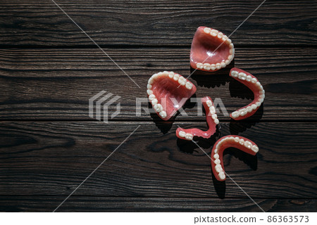 Dentures on a dark background. Close-up of dentures. Full removable plastic denture of the jaws. Prosthetic dentistry. False teeth. Close-up of plastic dentures. Teeth on a black background 86363573