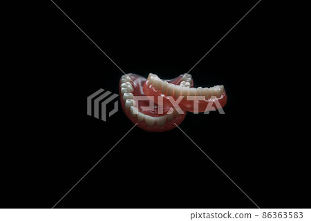 Full removable plastic denture of the jaws. A set of dentures on a black background. Two acrylic dentures. Upper and lower jaws with fake teeth. Dentures or false teeth, close-up. Copy space Full removable plastic denture of the jaws. A set of dentures on a black background. Two acrylic dentures. Upper and lower jaws with fake teeth. Dentures or false teeth, close-up. Copy space 86363583