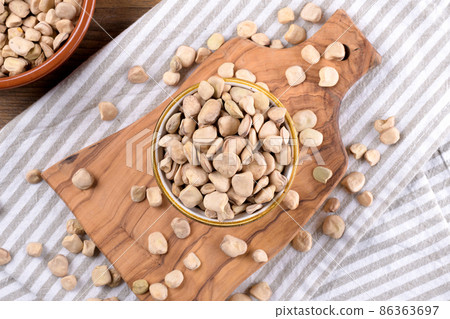 Cicerchia or indian pea on a ceramic bowl with napkin on natural wooden background, gluten free food. 86363697