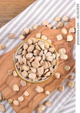 Cicerchia or indian pea on a ceramic bowl with napkin on natural wooden background, gluten free food 86363699