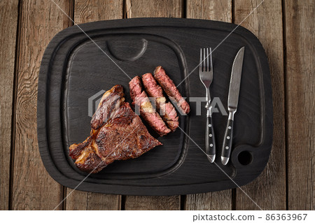 Top view of sliced veal entrecote on black board with cutlery Top view of sliced veal entrecote on black board with cutlery 86363967