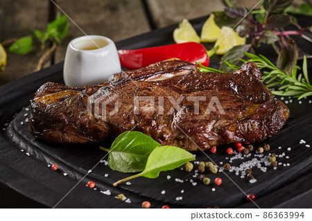 Closeup of fried veal entrecote on wooden board with condiments Closeup of fried veal entrecote on wooden board with condiments 86363994