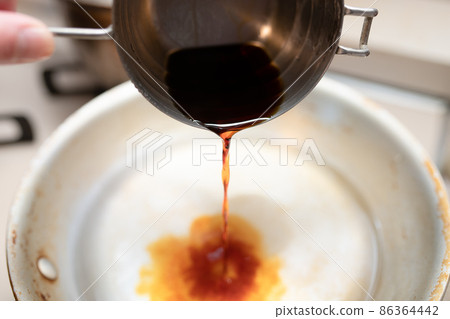 Pour soy sauce into the pot from the measuring cup 86364442