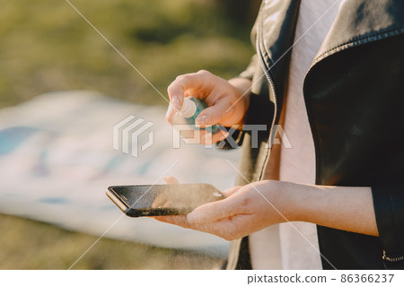 Woman treats her phone with antiseptic Woman treats her phone with antiseptic 86366237