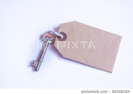 Key and brown paper tag on white background. Flat lay Key and brown paper tag on white background. Flat lay 86366264