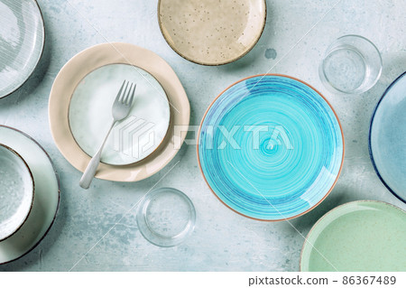 Modern tableware set with cutlery and a vibrant blue plate, overhead shot Modern tableware set with cutlery and a vibrant blue plate, overhead shot 86367489