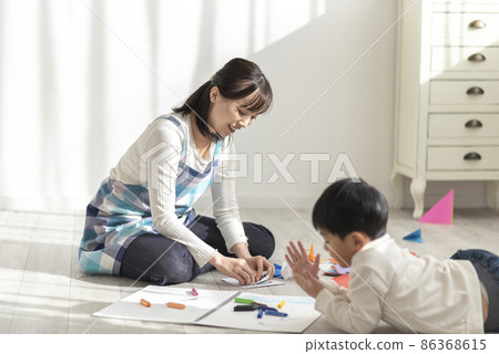 A 4-year-old boy and a nursery teacher playing with origami 86368615