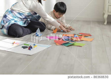 A 4-year-old boy and a nursery teacher playing with origami A 4-year-old boy and a nursery teacher playing with origami 86368630