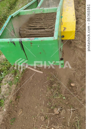 Tractor with mounted vibratory equipment for harvesting potatoes rips a row of potatoes, the process close-up. Tractor with mounted vibratory equipment for harvesting potatoes rips a row of potatoes, the process close-up. 86368861
