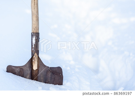 Metal shovel stuck with snow close-up. Snow removal in winter after a snowfall. Clearing snow in the home area. Metal shovel stuck with snow close-up. Snow removal in winter after a snowfall. Clearing snow in the home area. 86369197