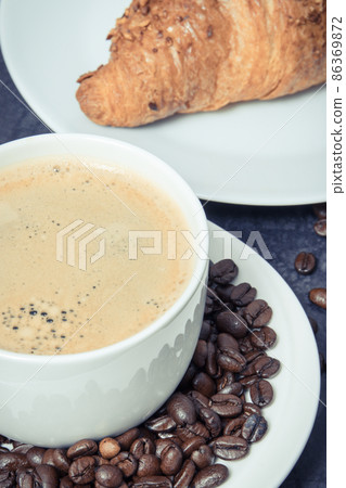 Breakfast consisting of fresh croissant with chocolate and coffee in white cup Breakfast consisting of fresh croissant with chocolate and coffee in white cup 86369872