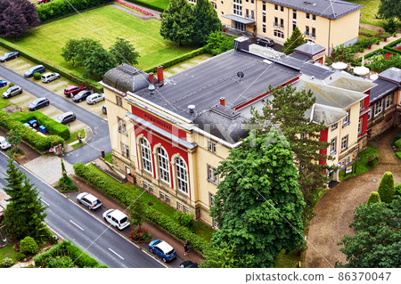 Aerial view of historical hotel in Bad Schandau in Saxony, Germany, with flat roof and parking place next to hotel Aerial view of historical hotel in Bad Schandau in Saxony, Germany, with flat roof and parking place next to hotel 86370047